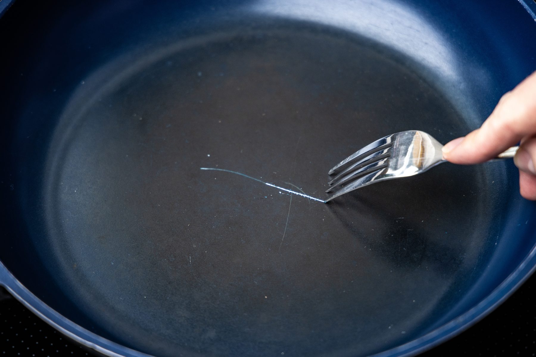 A fork scratching the surface of a non-stick pan